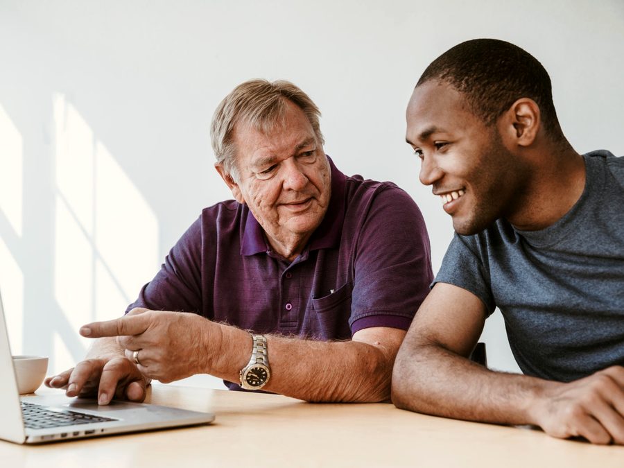 A young person and an older mentor working together at a laptop